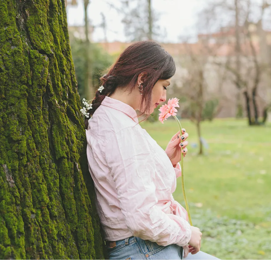 Woman smelling a flower practicing mindfulness; grounding techniques at Orlando Thrive Therapy.