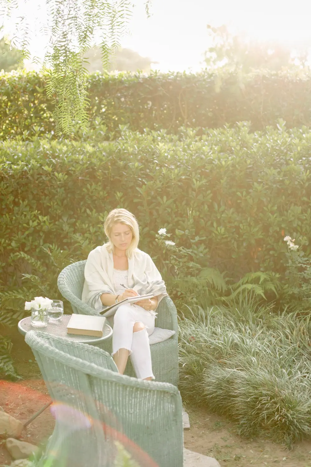 Woman journaling in a lush garden, representing the calm and supportive environment provided by Orlando Thrive Therapy in Altamonte Springs.