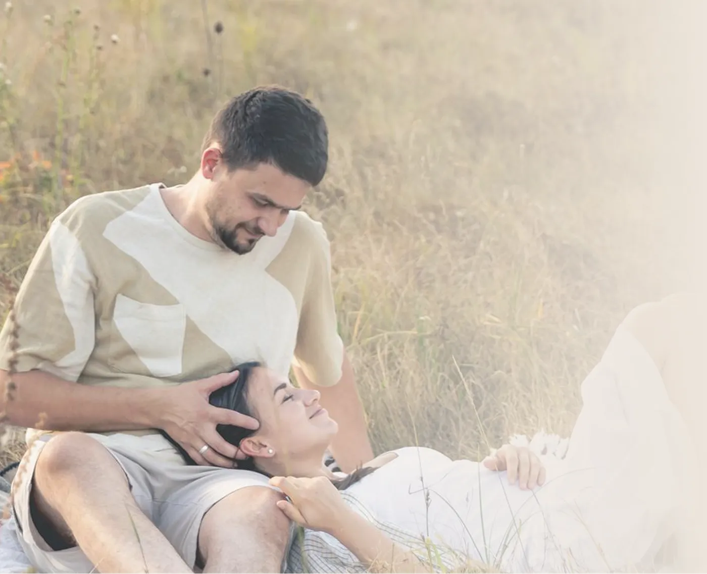 A couple resting together in a sunlit field, reconnecting after working through the strain ADHD placed on their relationship.